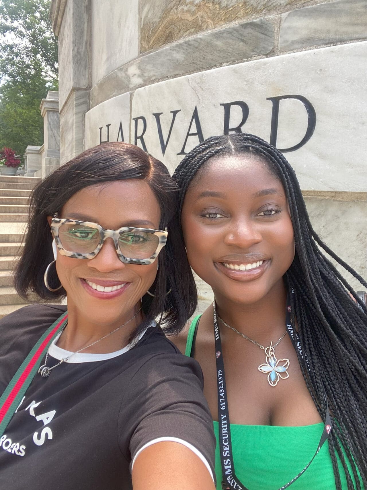 Adja Camara and a loved one smiling in front of the Harvard University sign.